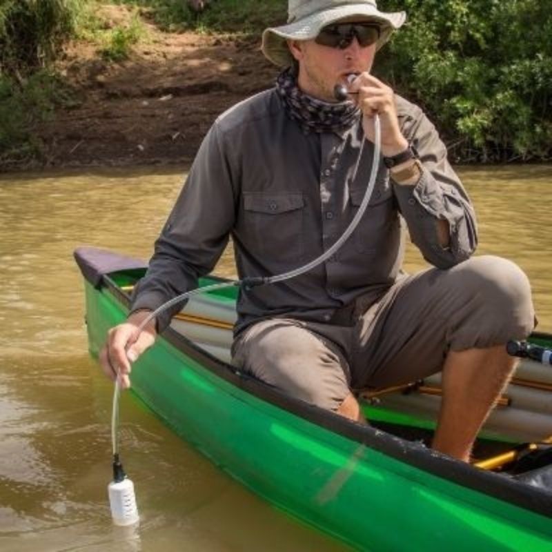 man in canoe using straw water purifier