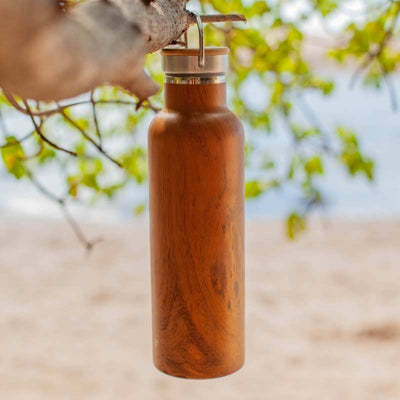 classic elemental teak water bottle hanging on tree near beach